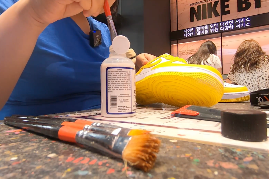Applying finishing touches on yellow Nike Air Force sneakers at Nike By You