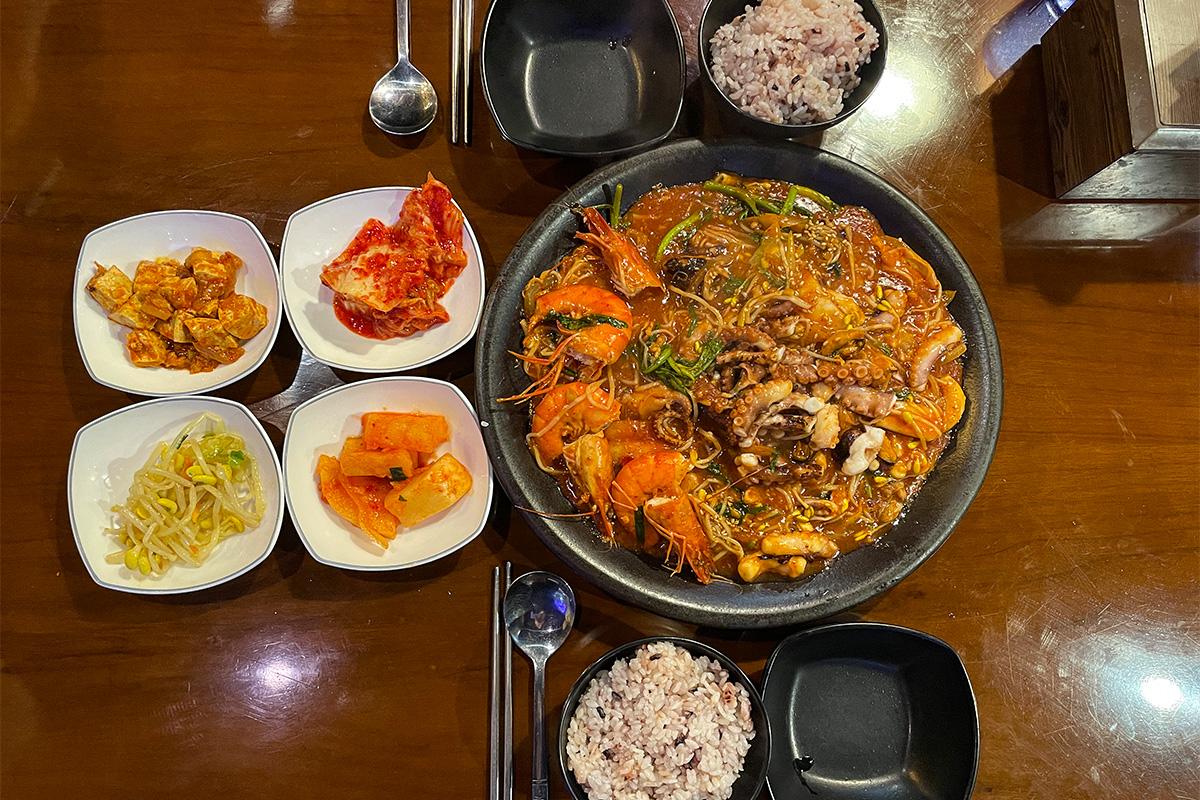长今煎家的丰盛韩国大餐，配有辣炒海鲜、米饭和多款泡菜。