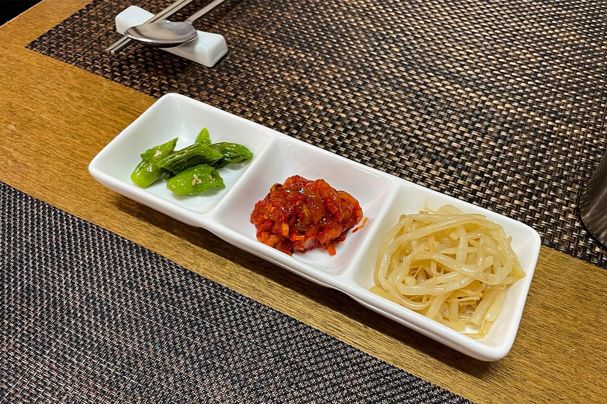 瑞源粥店提供的基本小菜，包括炒青龙椒、凉拌豆芽和老板自制鱿鱼酱。