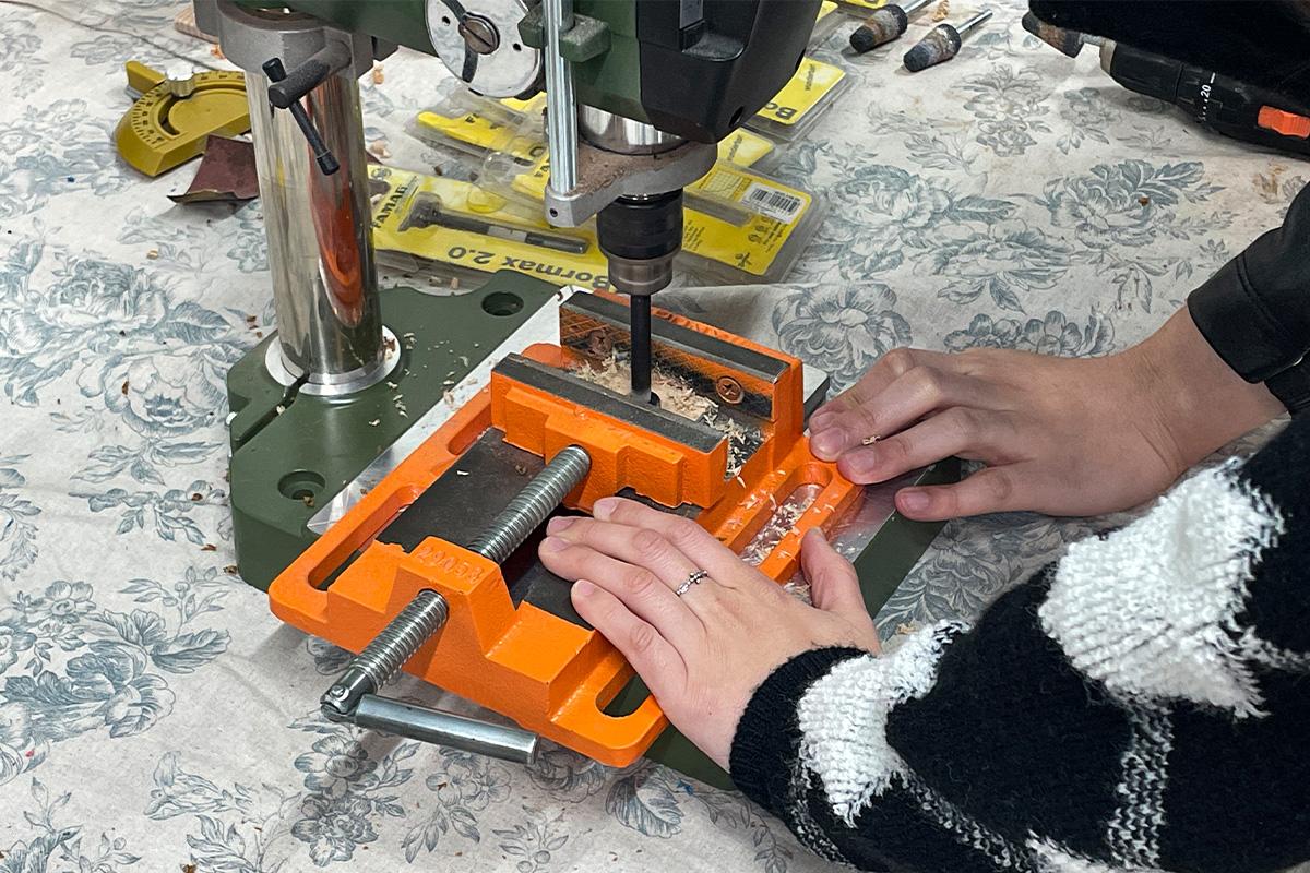 Wetwood Studio 的顾客正在使用钻床进行木材的打孔过程，展示驾驶位置上的安全操作。