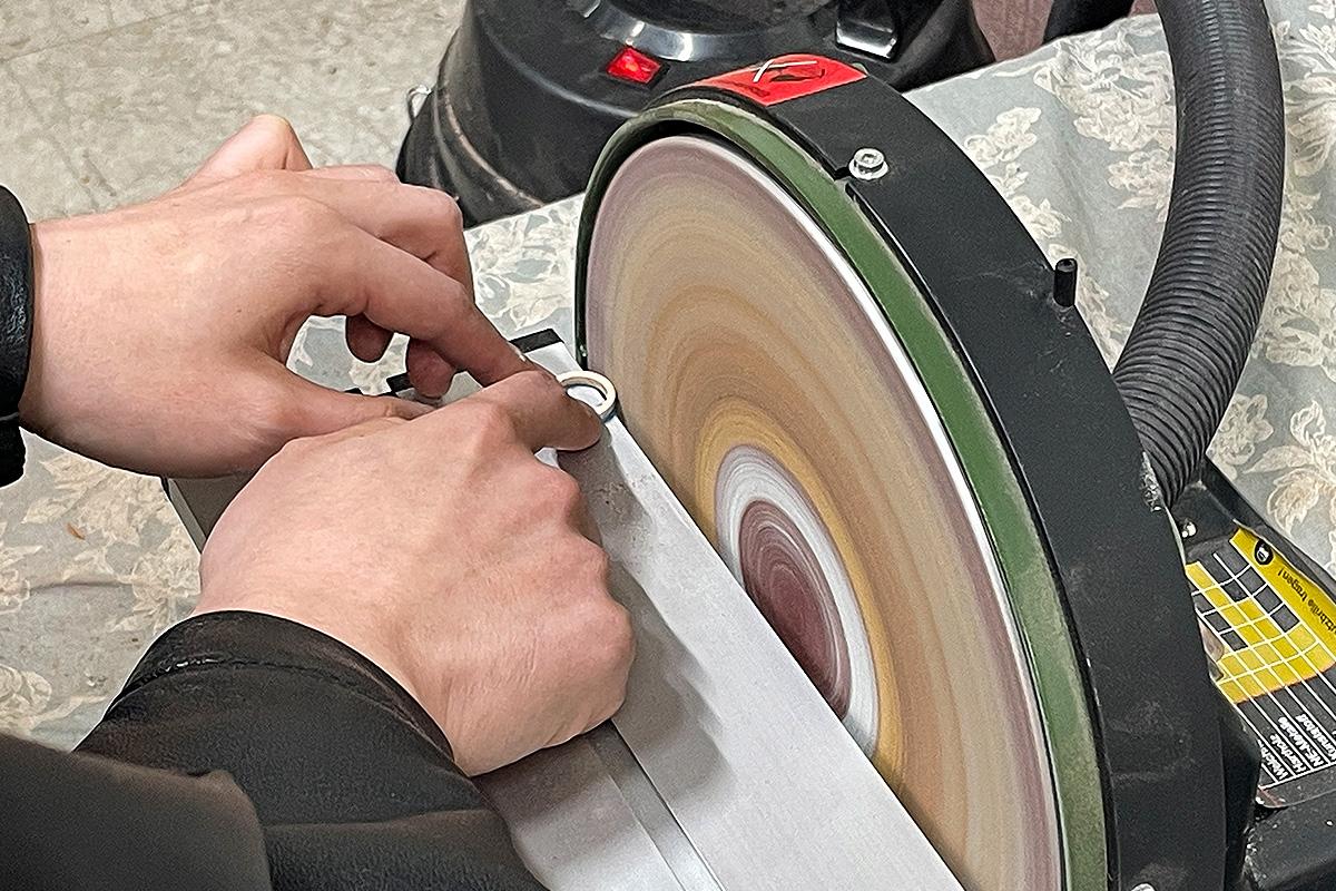 顾客在Wetwood Studio 中使用砂轮机打磨木戒指，提升表面光滑度，为成品做准备。