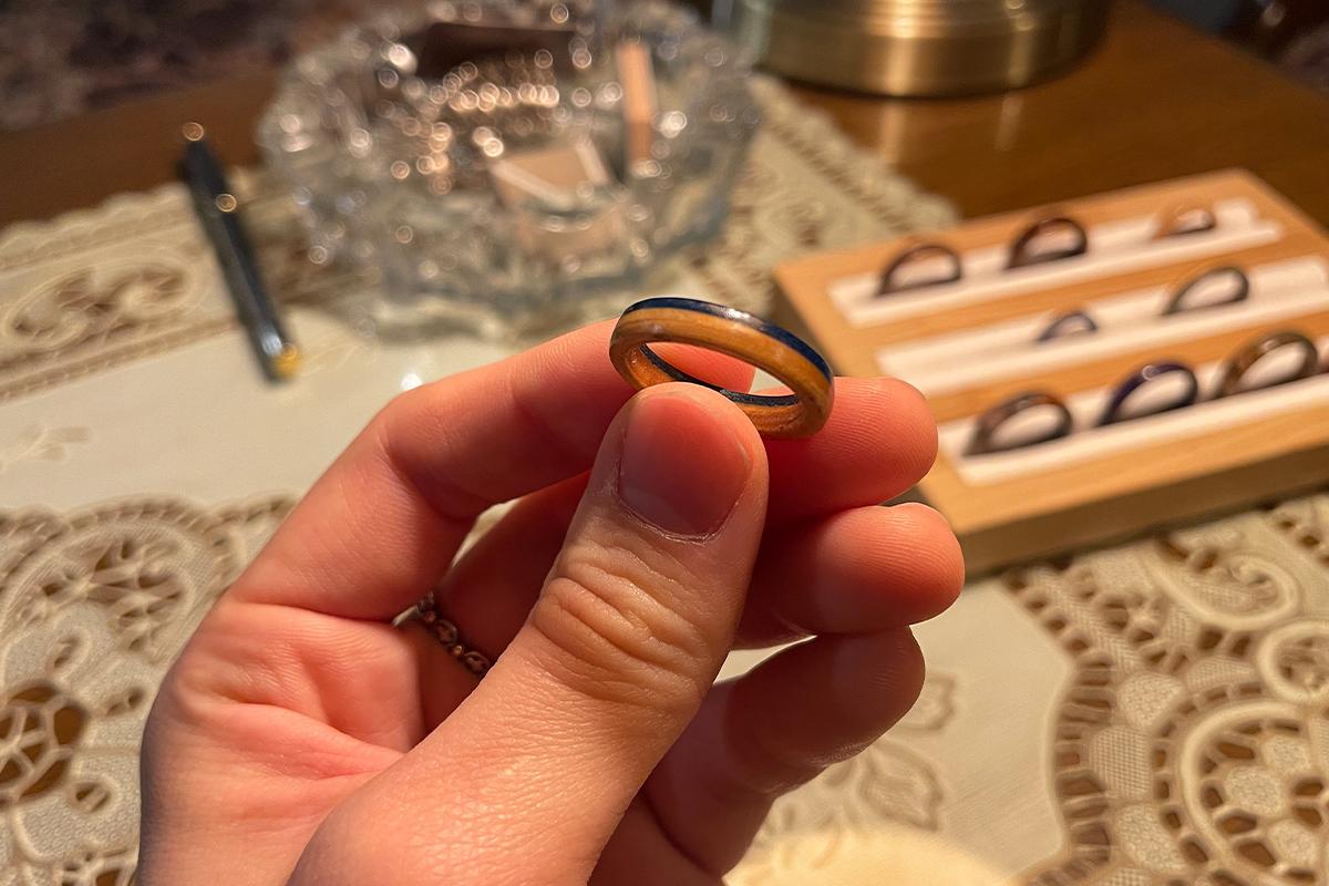Wetwood Studio 的顾客展示刚制成的蓝色环型木戒指，成品置于圆形盘中。
