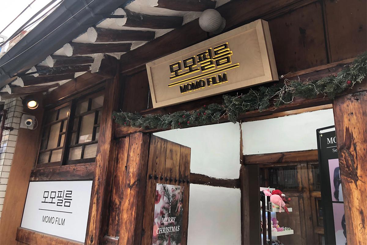 Eksterior toko Momo Film di Ikseon-dong, menarik wisatawan dengan papan kayu dan dekorasi.