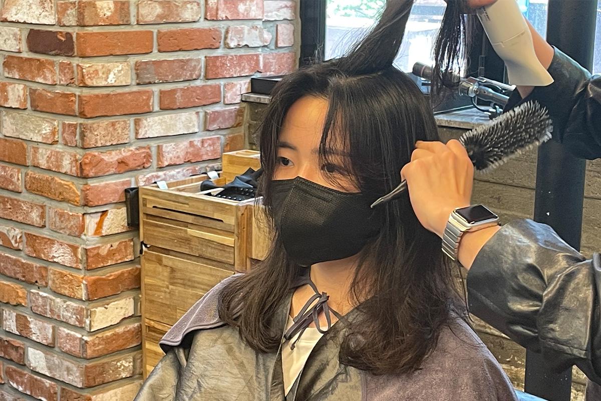 髮型設計師正在拉直顧客的捲髮,以保持美麗造型。