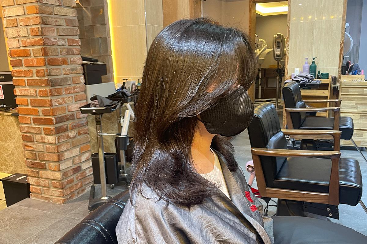 一位顧客在沙龍內接受髮型師用間隙梳打理她的捲髮。