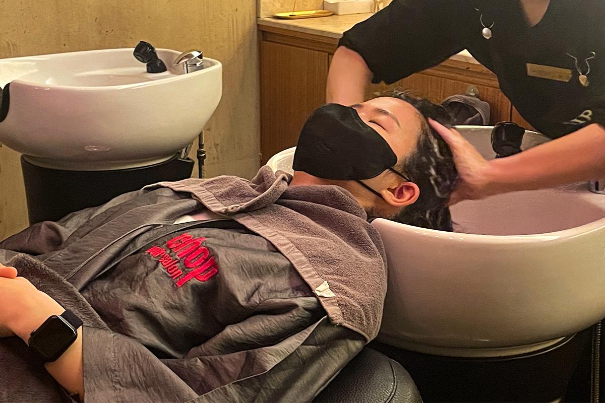 一位客人在美容沙龍的洗髮區洗頭,享受專業護理服務。