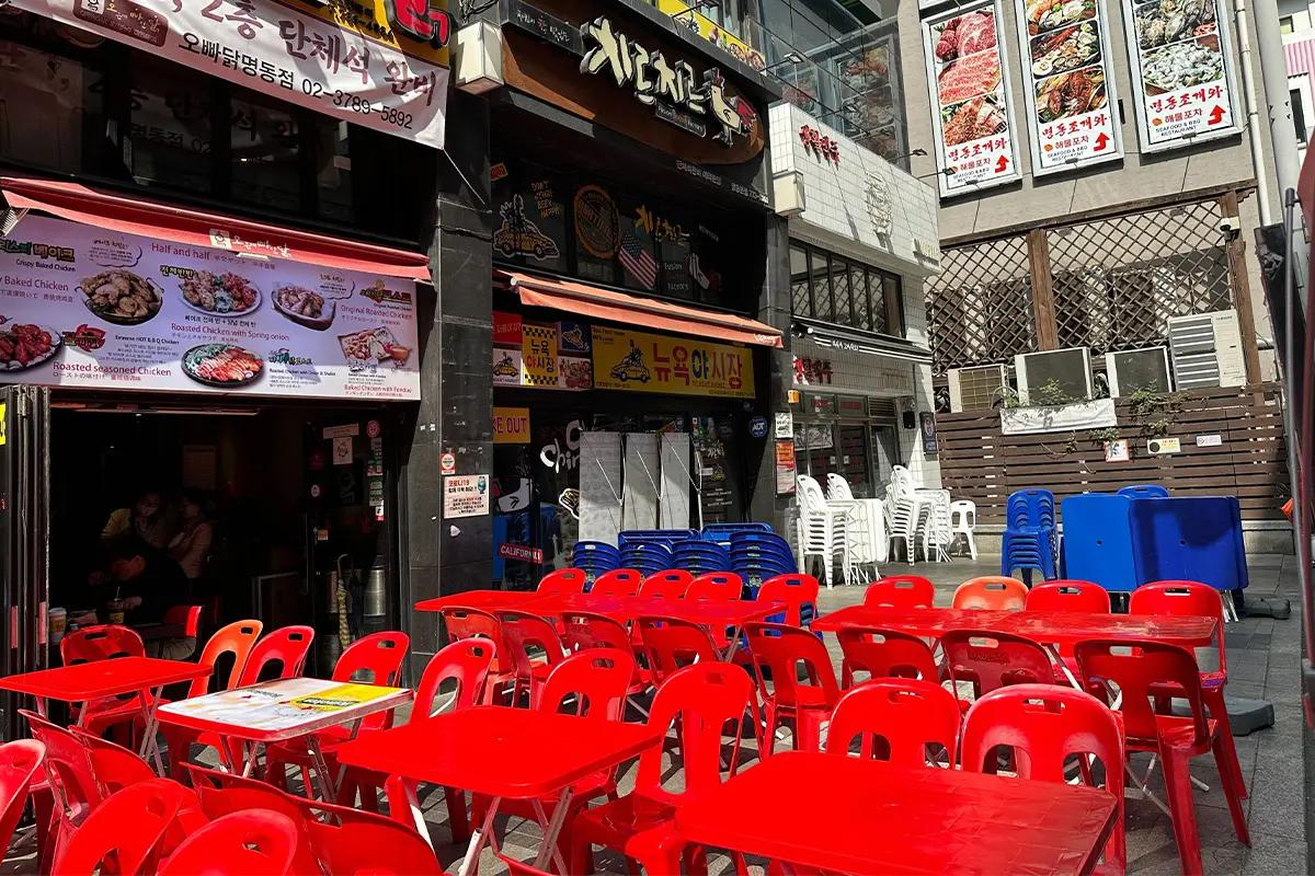 ソウルの明洞にあるオッパダッの外観、地元の人気のベイクドチキンレストランとそのメニューの写真が看板に表示されています。オープンエアのテラス席があり、魅力的な食事体験を提供しています。
