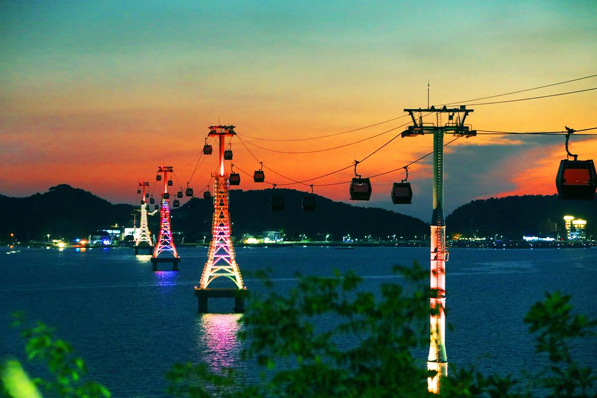 Teleférico Seohae-Rang iluminado al atardecer sobre el mar cerca de Ansan, Corea, con un horizonte colorido.
