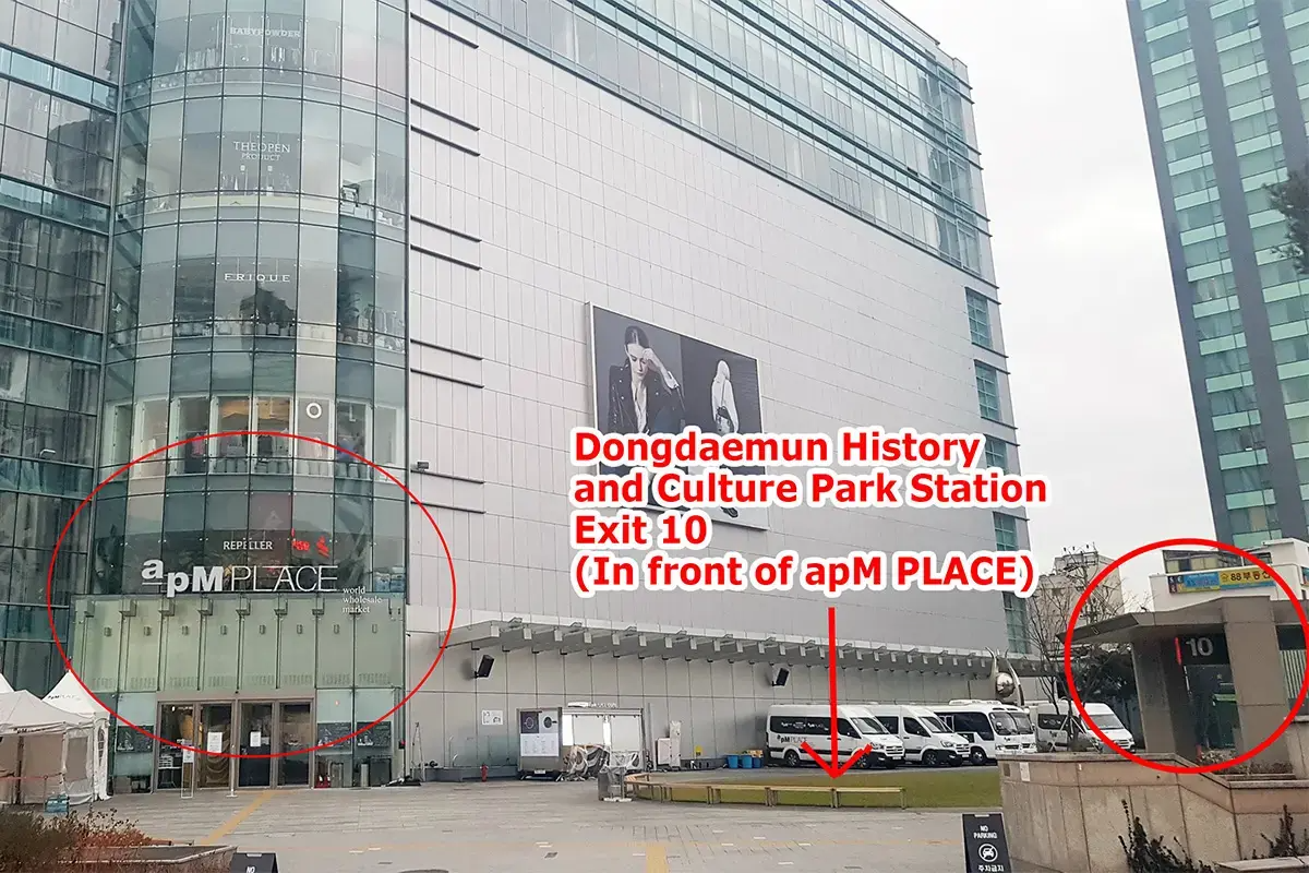 รูปถ่ายด้านหน้าสถานี Dongdaemun History and Culture Park ทางออก 10 ในเกาหลี มีป้ายสถานีและเค้าคล้ายตึกสูงในพื้นหลัง