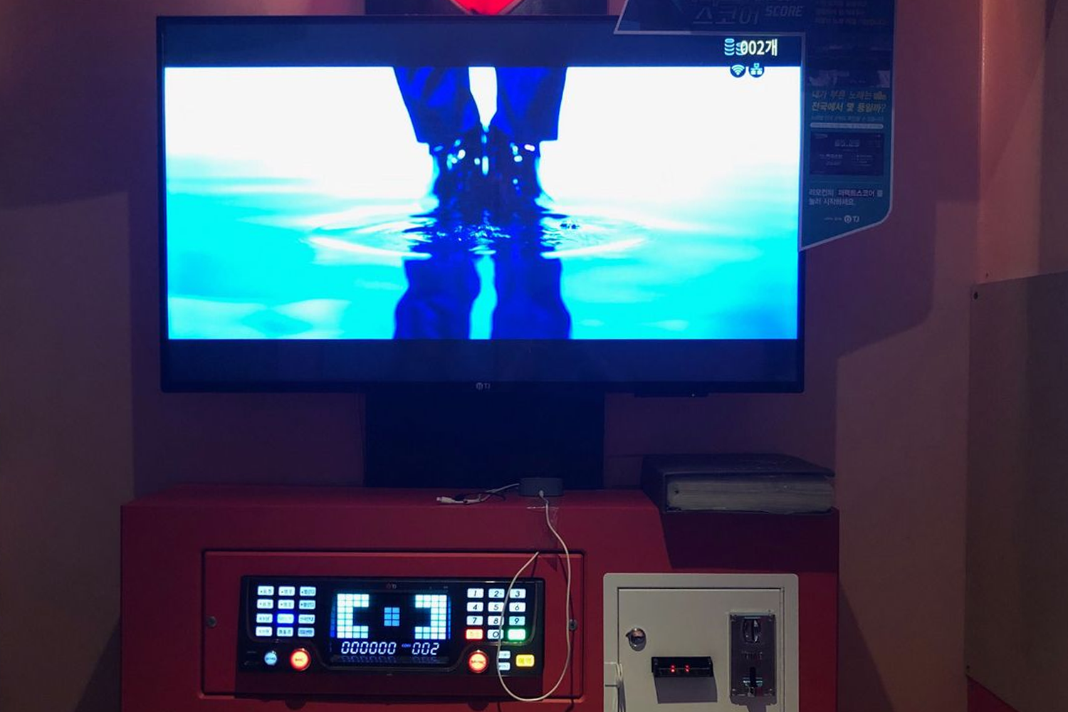 Inside view of a Korean coin karaoke room with a screen and control panel for song selection.