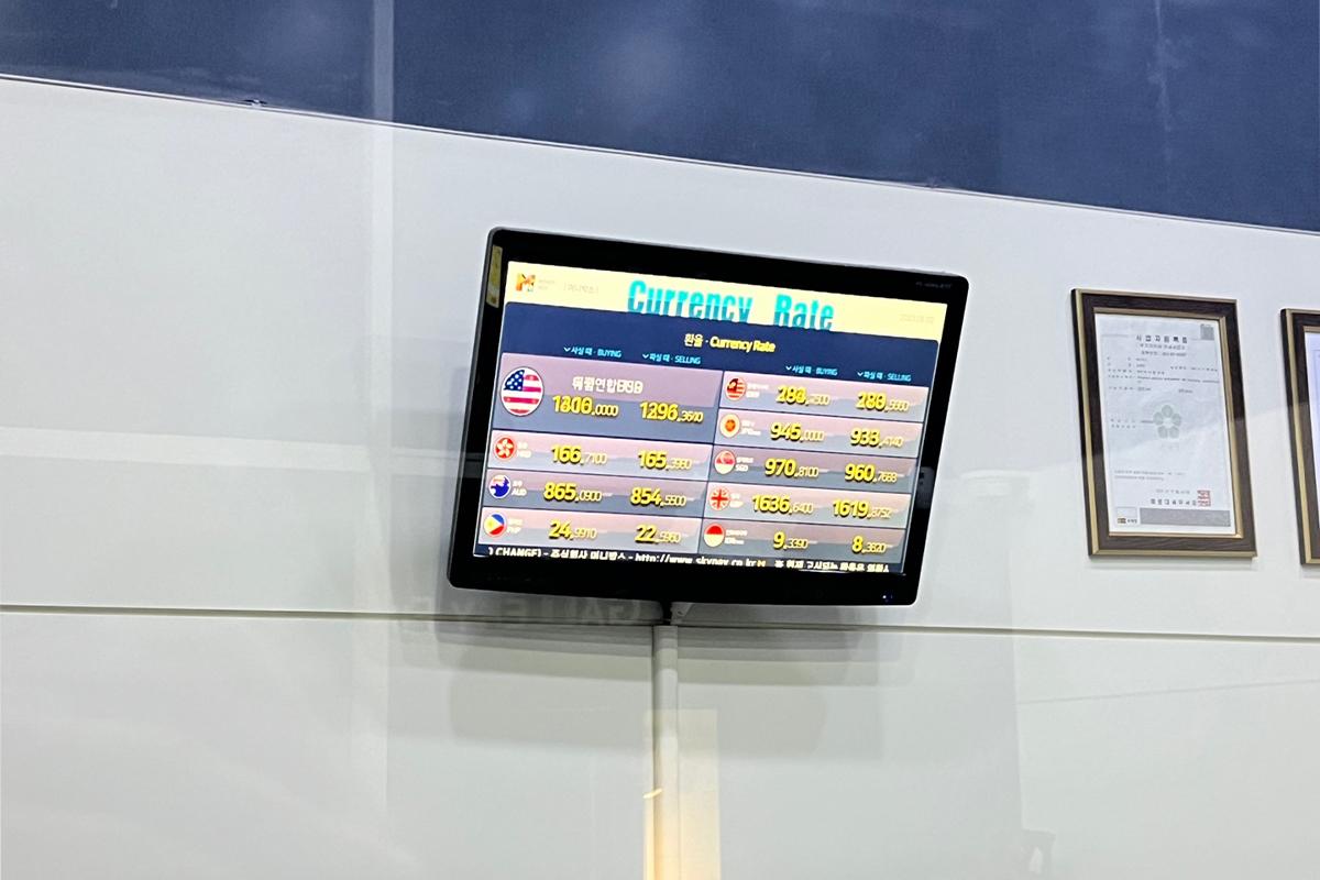 Currency exchange counter at Money Box Haeundae branch with electronic display showing current exchange rates.
