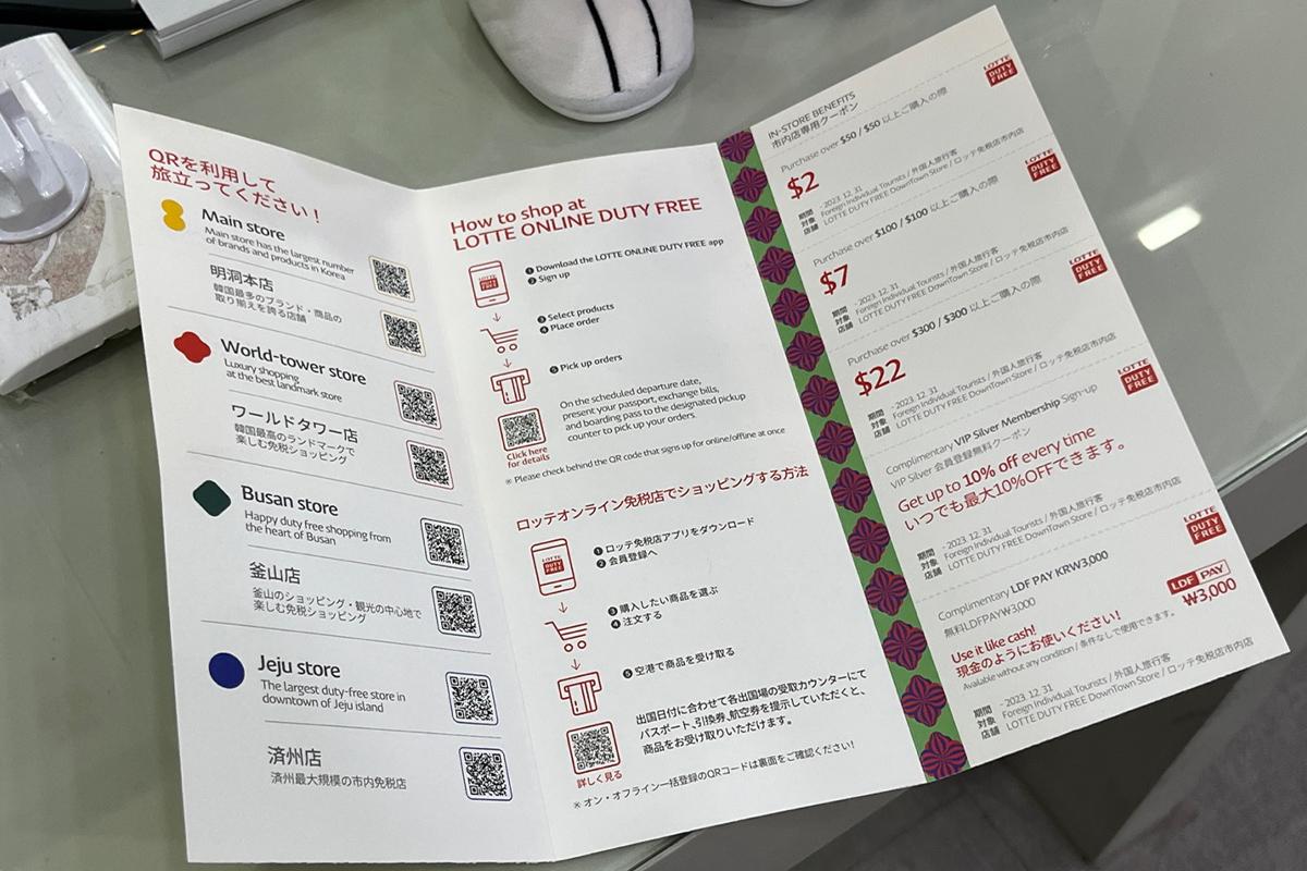 Lotte Duty Free brochure on display at Money Box Haeundae counter, detailing shopping benefits for tourists.
