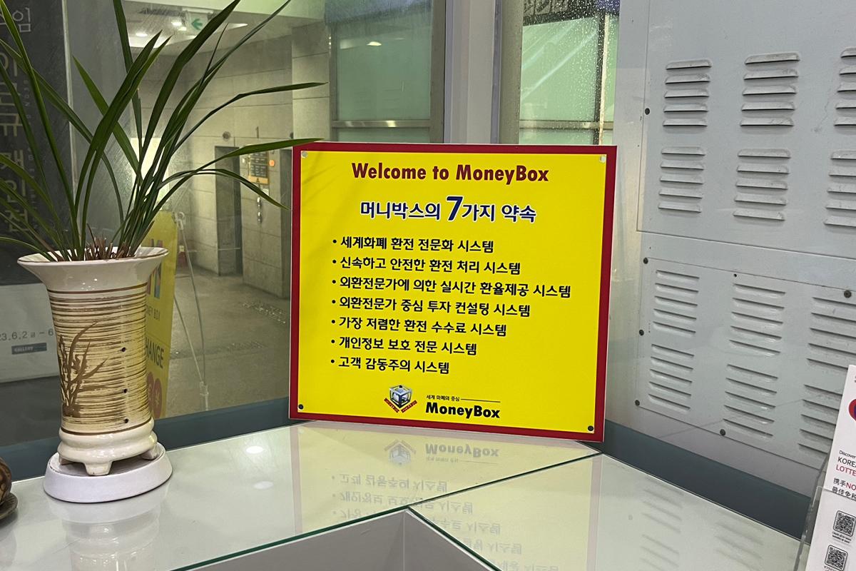 Welcome signage detailing Money Box's currency exchange promises at the Haeundae branch in South Korea.