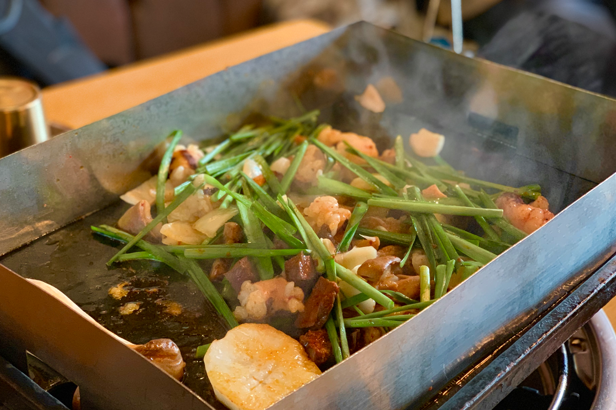 鐵板上正在翻炒的韓國燒腸，夾雜著蔬菜配料