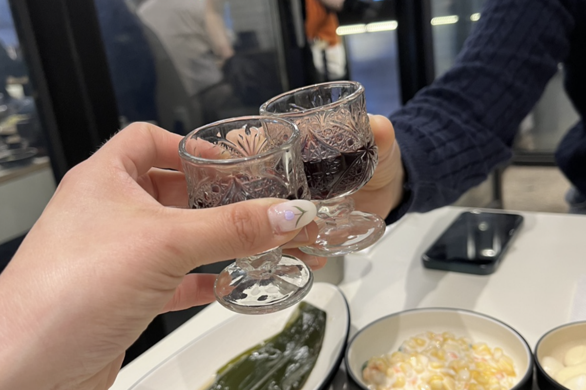 Imagen de dos personas brindando con bebida en barbacoa de Dadokine, restaurante en Hapjeong.