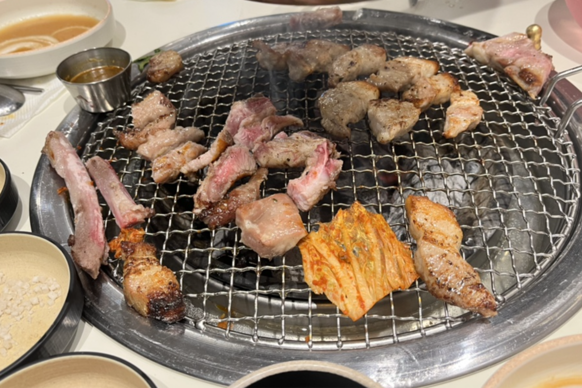 Carne de cerdo samgyeopsal asándose sobre fuego con kimchi en Dadokine, Hapjeong.