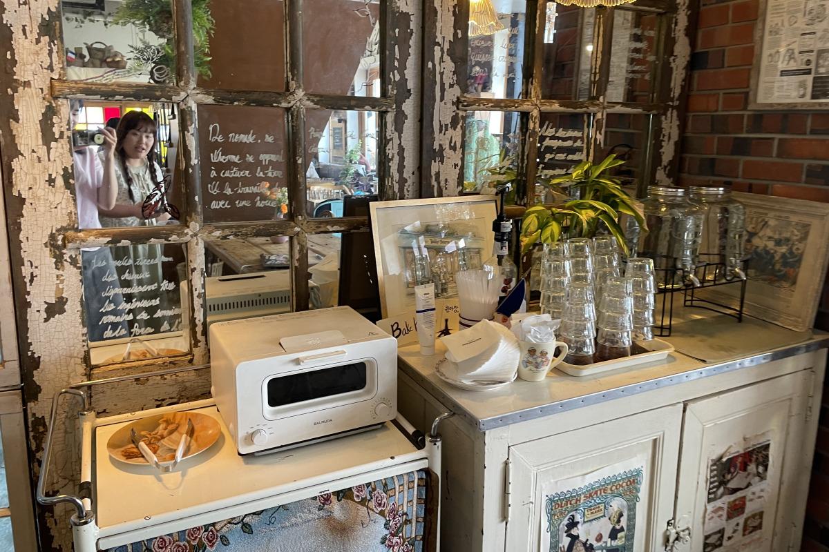 Sección de autoservicio de Teddy Beurre House con un horno tostador y utensilios para calentar y servir pan.