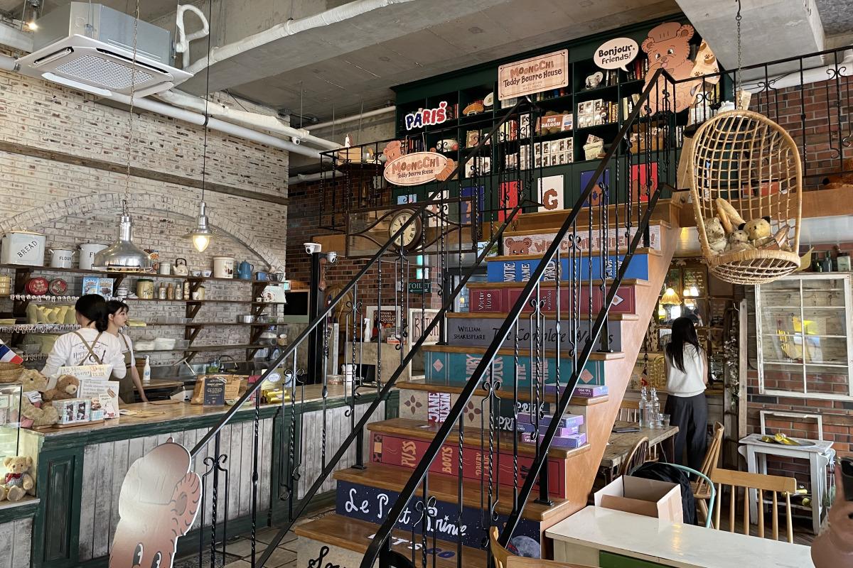 Interior del Teddy Beurre House mostrando una escalera decorada con temas de libros y un columpio colgante para osos de peluche.