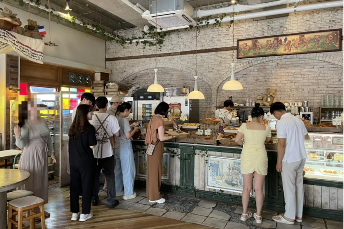 Interior del Teddy Beurre House en Yongsan con varios clientes haciendo fila para ordenar croissants y café.