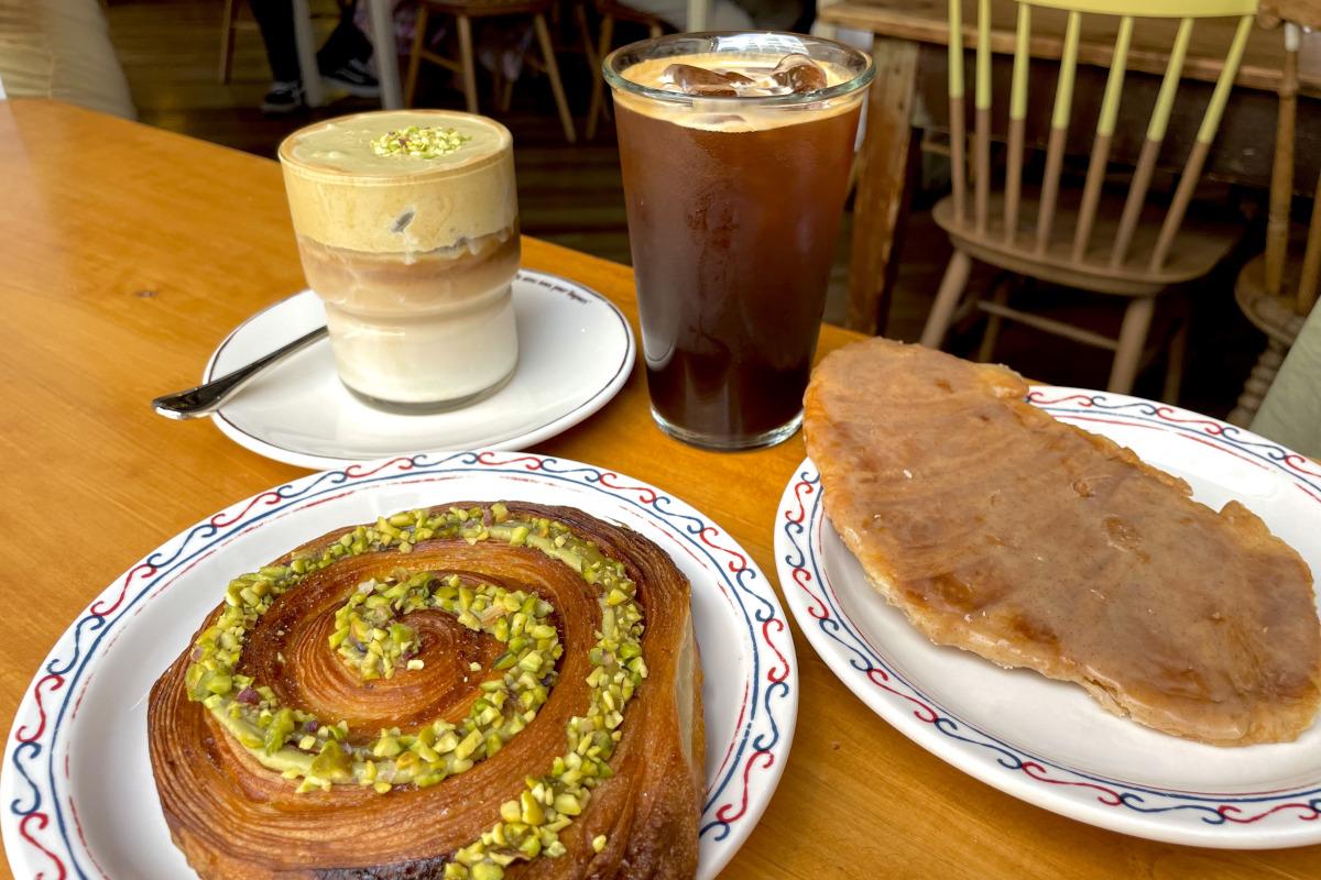 Una mesa en Teddy Beurre House con un café con leche de pistacho, americano y una selección de pastelería.