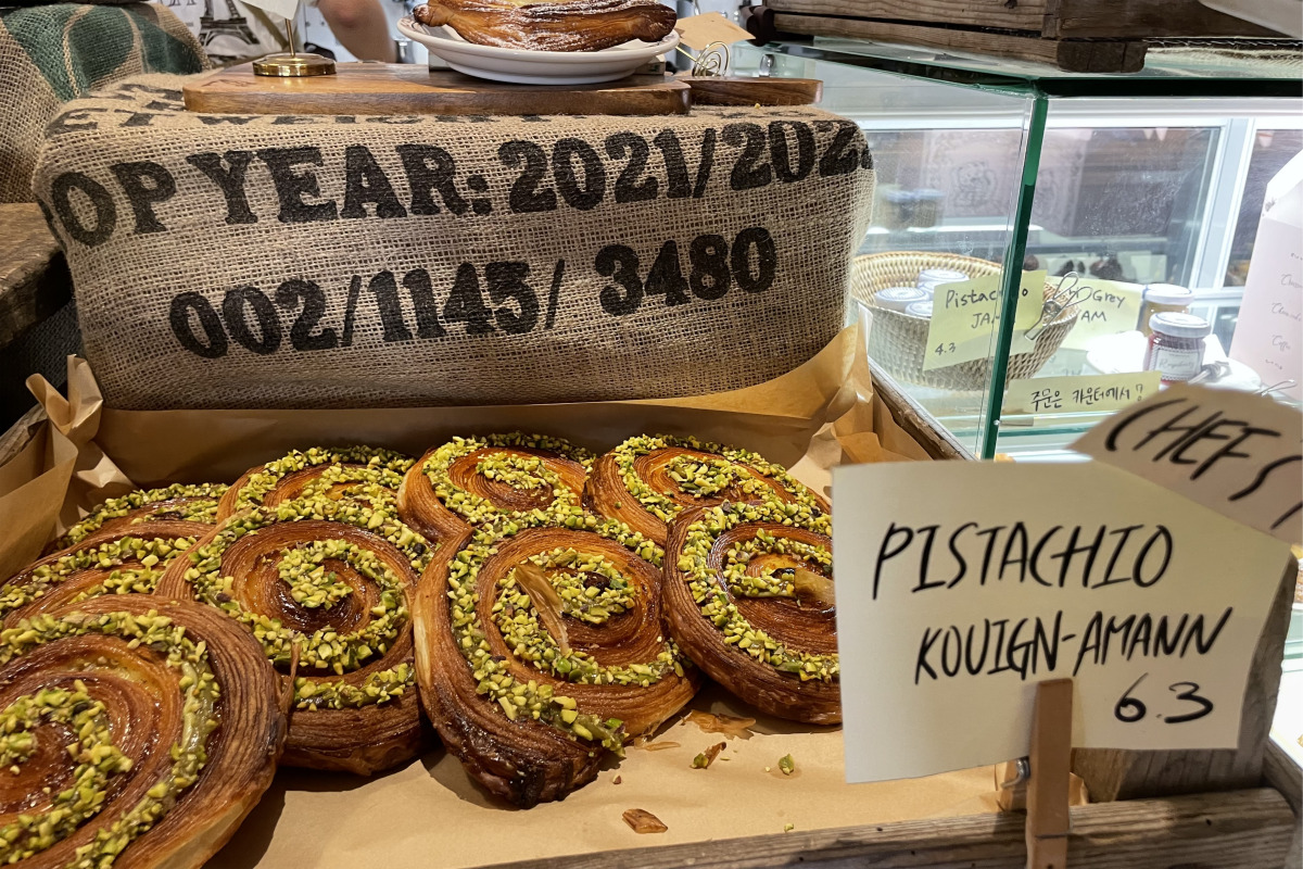 Pastelería que incluye Kouign-Amann de pistacho, con una capa de pistachos en la cima, en Teddy Beurre House.
