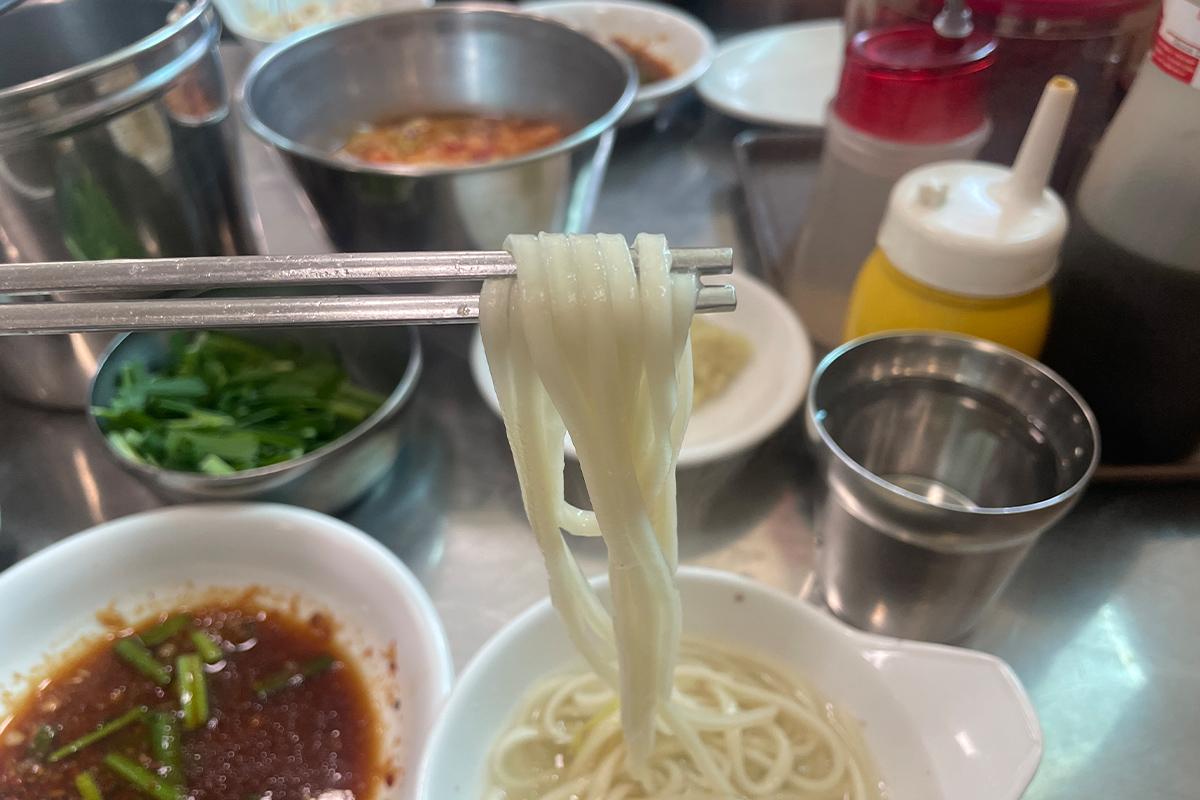 明洞一隻雞（巨成店）的招牌正面，上面有不同語言標示的店名，如韓文、漢字、日文等。