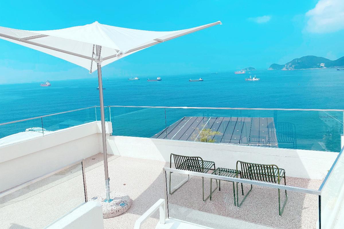 Weitreichende Aussicht auf das azurblaue Meer von einer Terrasse im Yeoulmarq Cafe.