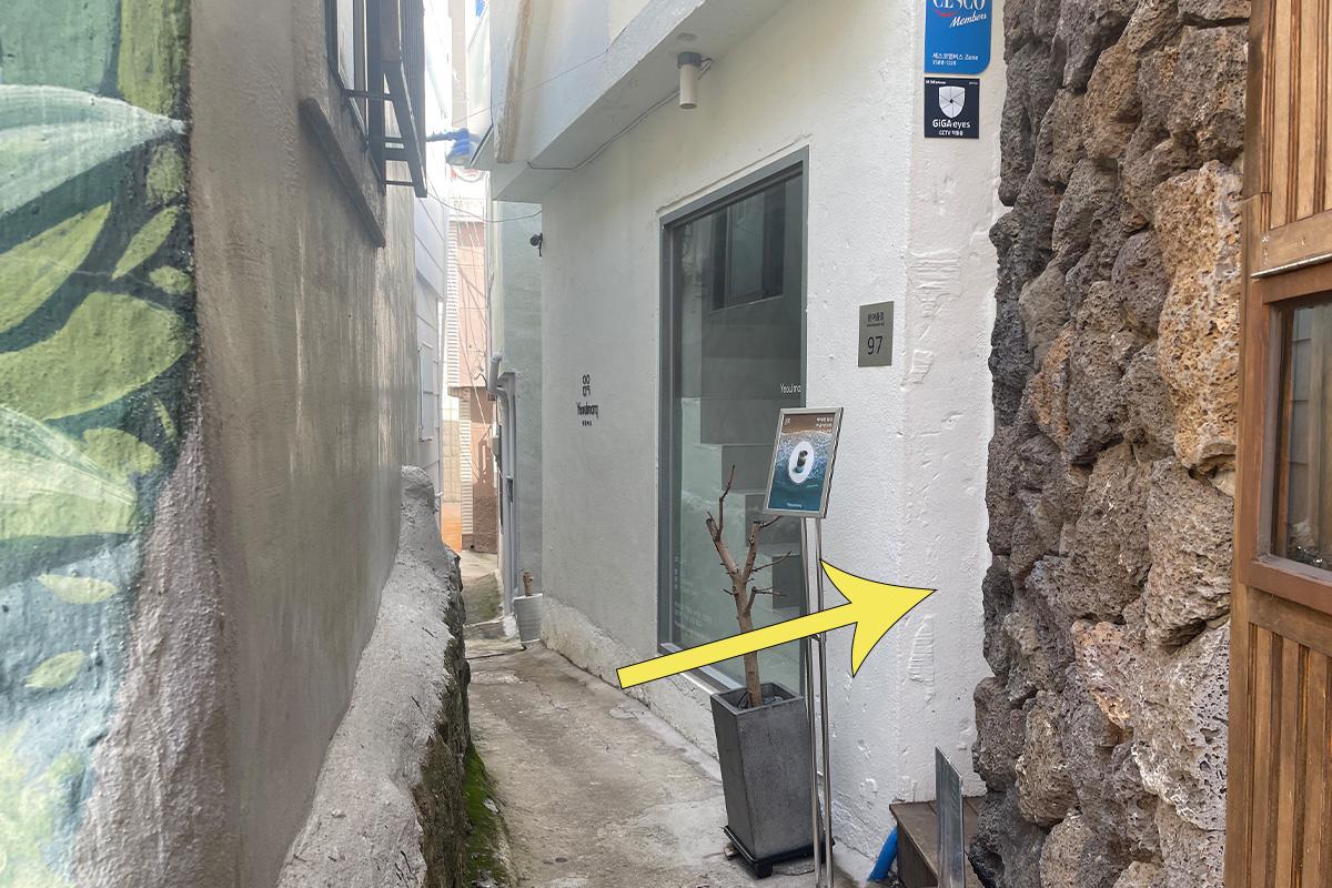 Eingang zum Yeoulmarq Cafe durch einen mit Pflanzen dekorierten Korridor.