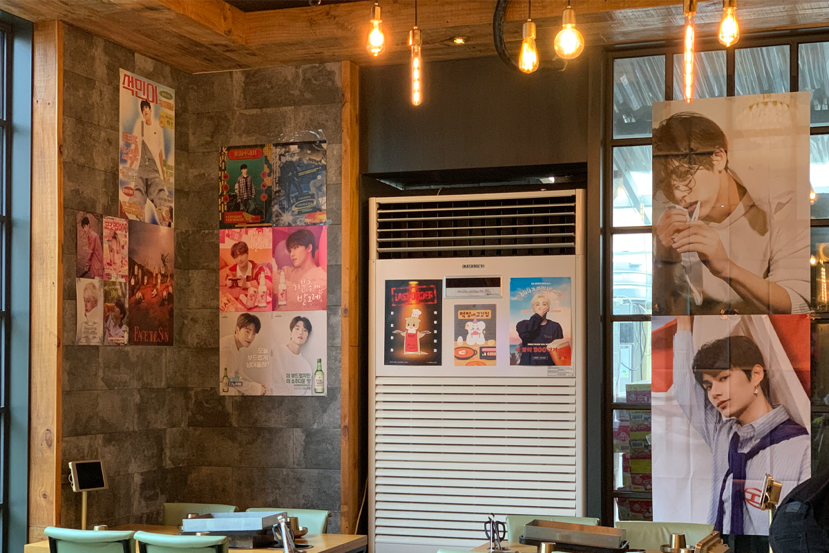室內牆面掛著韓國偶像團體的宣傳海報與廣告畫面