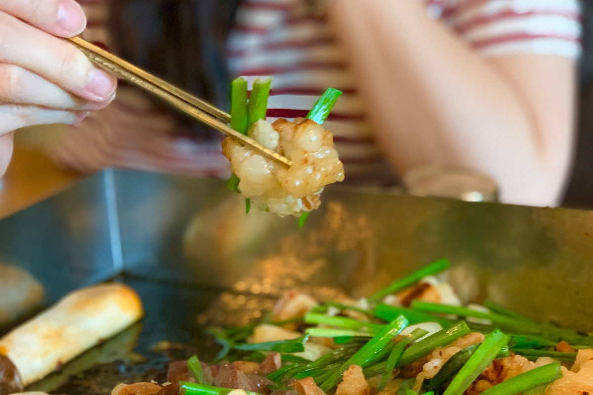 女顧客使用筷子夾起美味的腸類燒烤