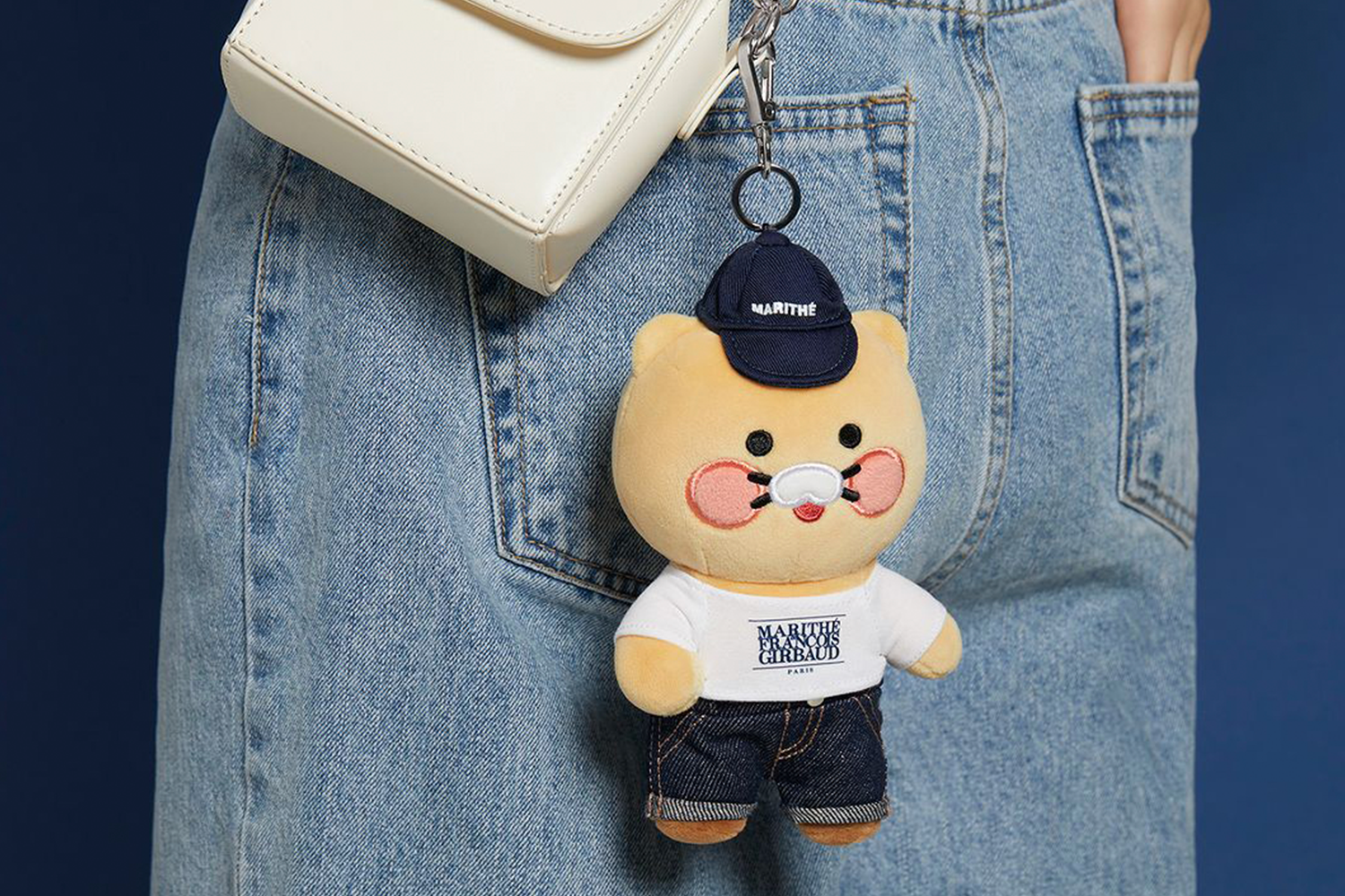 Marithe和Kakao Friends联名款挂饰展示：背带裤装扮的莱恩玩偶挂在模特牛仔裤口袋边上，品牌巧妙地结合了卡通人物的可爱元素和时尚牛仔风格，体现出独特的韩流潮流魅力。