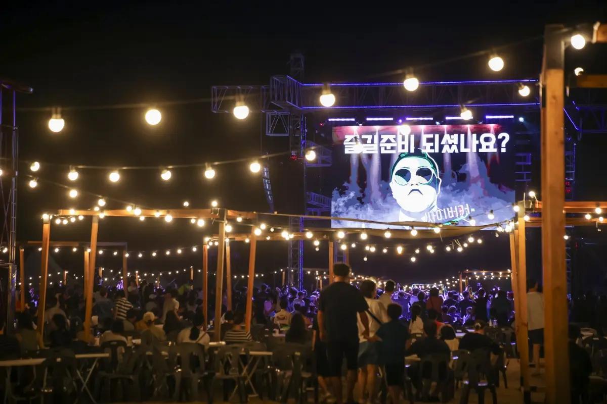 Audience watching a nighttime outdoor stage under string lights at the Busan Sea Festival
