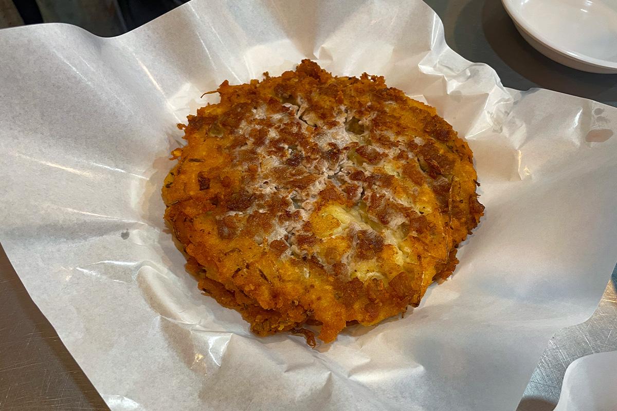 Ein traditioneller koreanischer Fleischpfannkuchen, serviert im Gwangjang-Markt in Seoul auf weißem Papier.