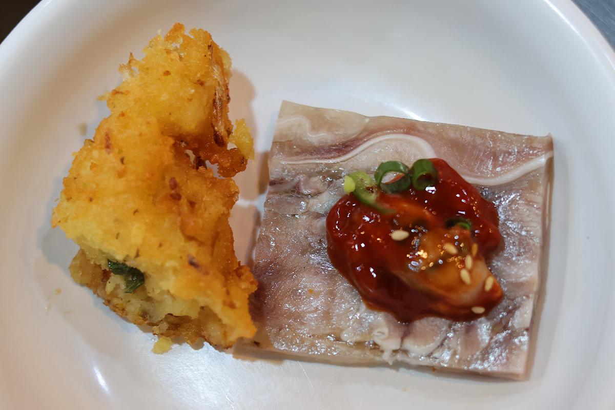 Ein Stück yukjeon mit Pajeori im Parkgane Bindaetteok auf dem Gwangjang-Markt in Seoul, gehalten mit Essstäbchen.