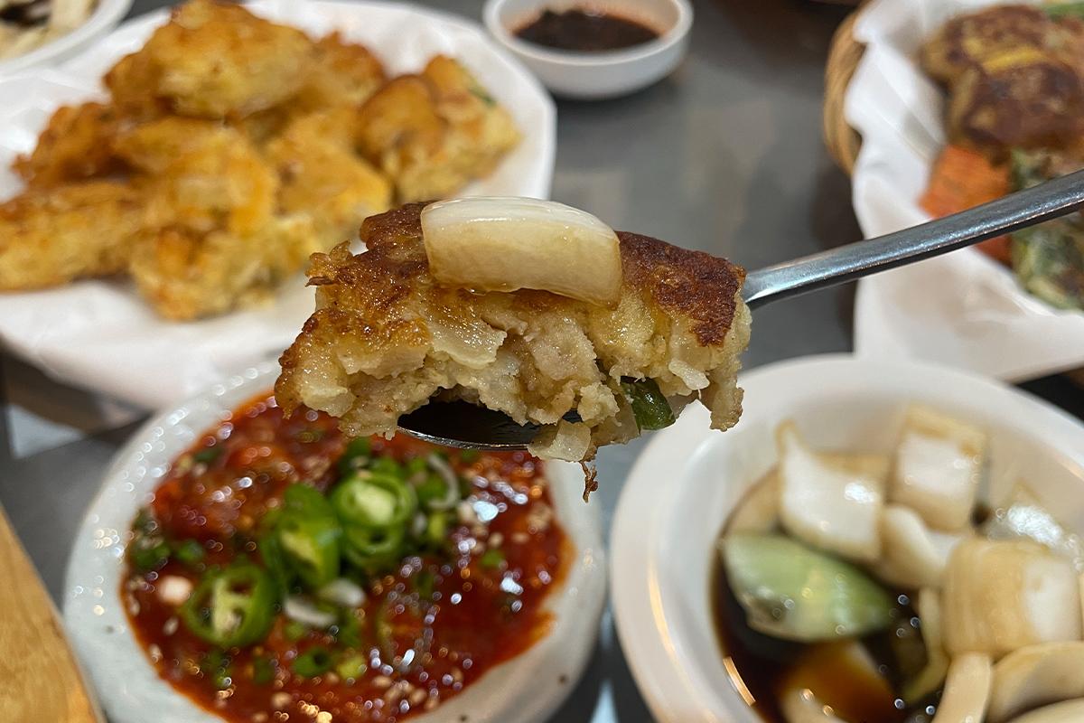 Kartoffel-Buchimgae, kräftig und geschmackvoll, auf einem Esstisch im Parkgane Bindaetteok auf dem Gwangjang-Markt, Seoul.