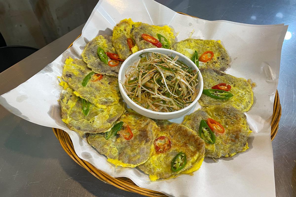 Ein Teller Hanwoo Yukjeon (koreanischer Rindfleischpfannkuchen) mit Frühlingszwiebelsalat auf dem Gwangjang-Markt in Seoul.