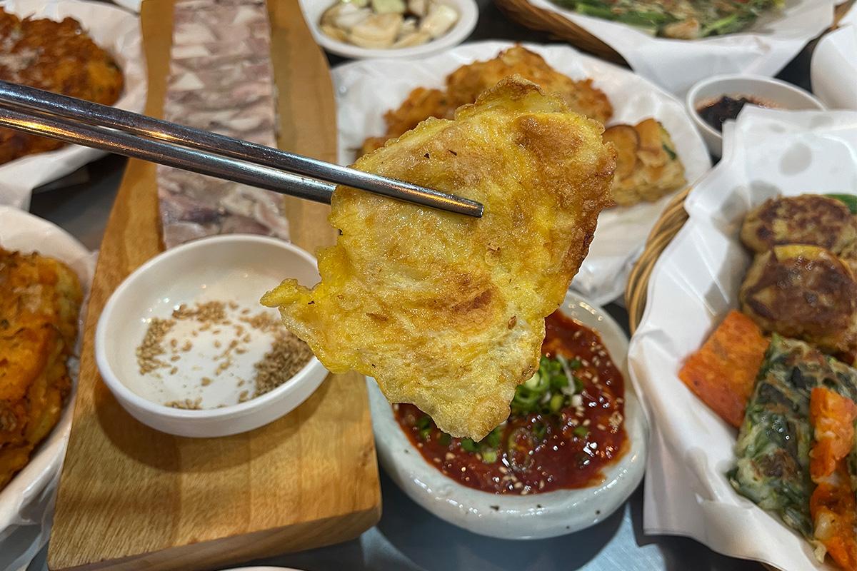 Kartoffel-Buchimgae, knusprig gebratene koreanische Kartoffelpuffer, serviert im Parkgane Bindaetteok auf dem Gwangjang-Markt, Seoul.
