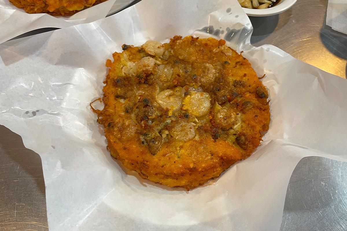 Ein traditioneller koreanischer Meeresfrüchte-Pfannkuchen auf weißem Papier serviert im Gwangjang-Markt in Seoul.