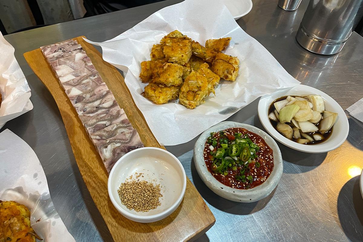 Ein Gericht mit Parkgane Samhap, bestehend aus Bindaetteok, Schweinefleisch und Austern-Kimchi auf dem Gwangjang-Markt in Seoul.