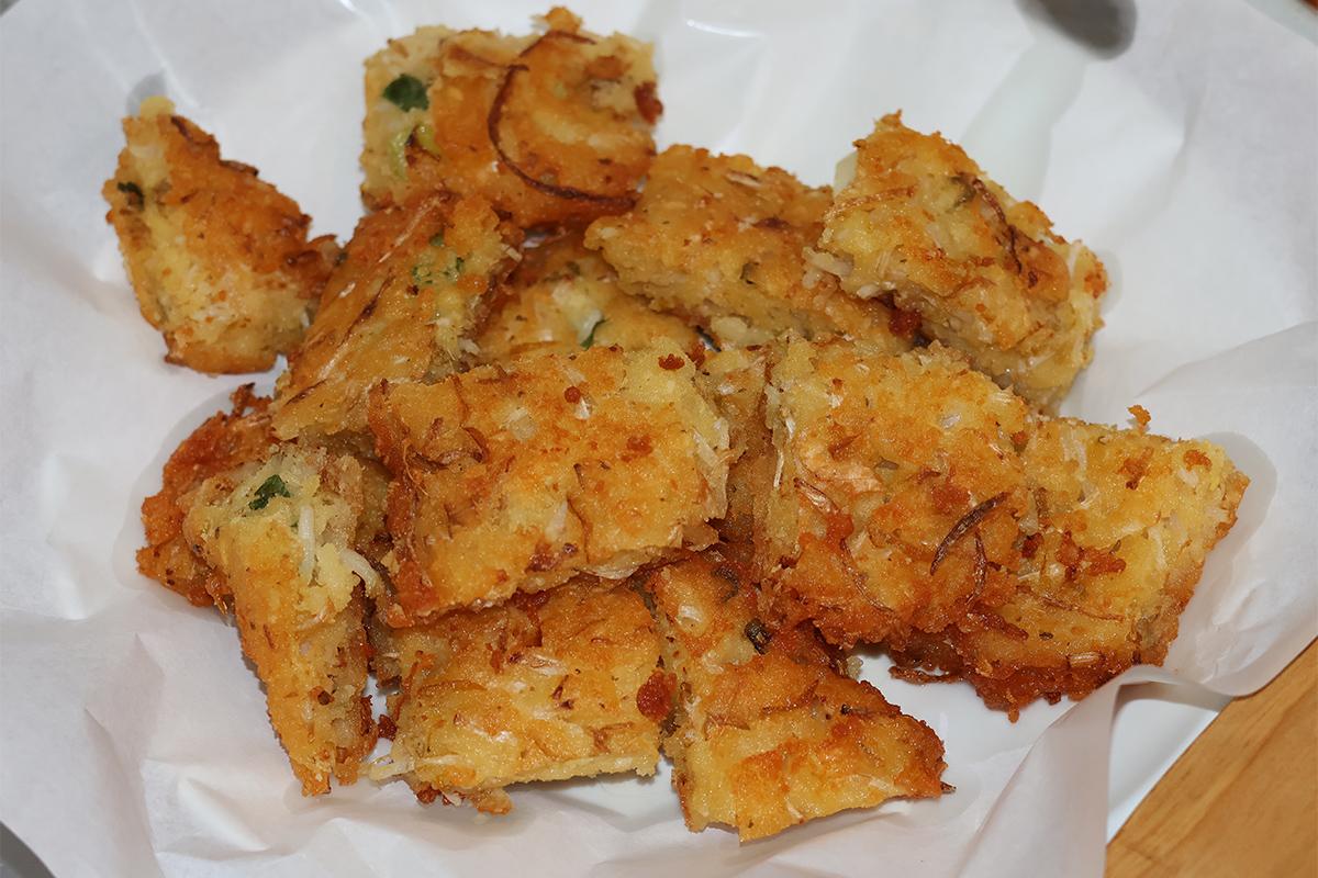 Ein Stück Bindaetteok mit knuspriger Kruste und Essigzwiebel, serviert im Parkgane Bindaetteok auf dem Gwangjang-Markt, Seoul.