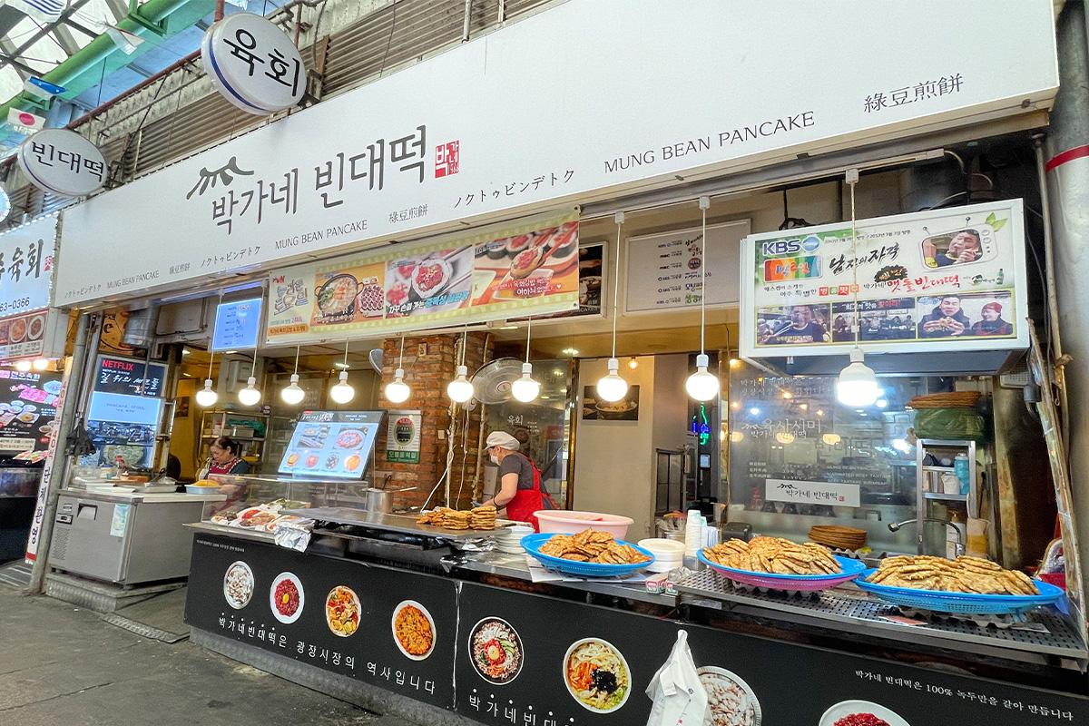 Ein Bindaetteok auf einem Löffel, getränkt in Essig, serviert im Parkgane Bindaetteok auf dem Gwangjang-Markt, Seoul.