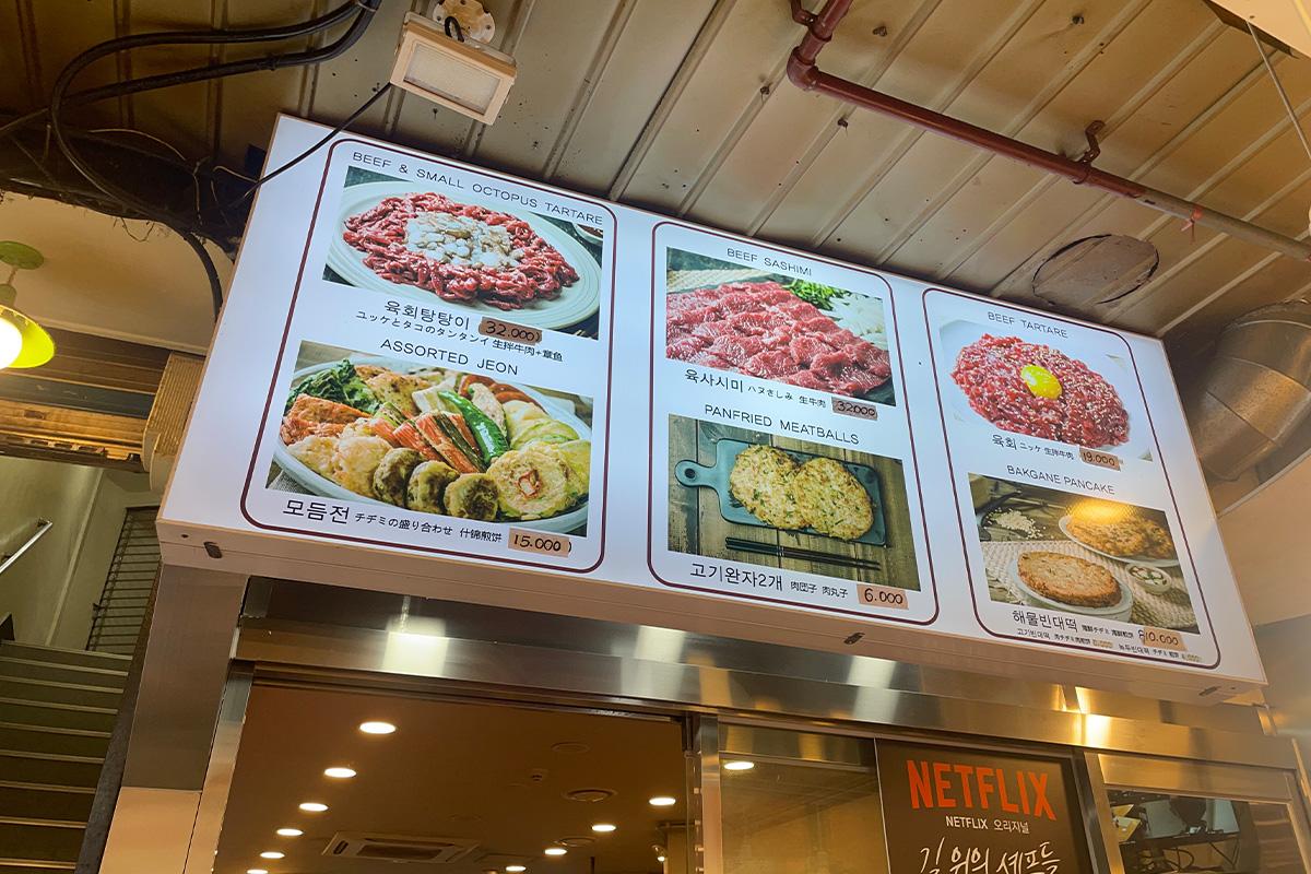 Vista del menú en el restaurante Bakgane Yukhoe en el Mercado Gwangjang, ofreciendo platillos como Yukhoe y Yukhoe Tangtangi