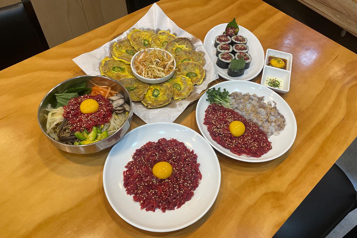 Mostrador de preparación de Yukhoe en Bakgane Yukhoe con carne fresca y yemas de huevo en exhibición.