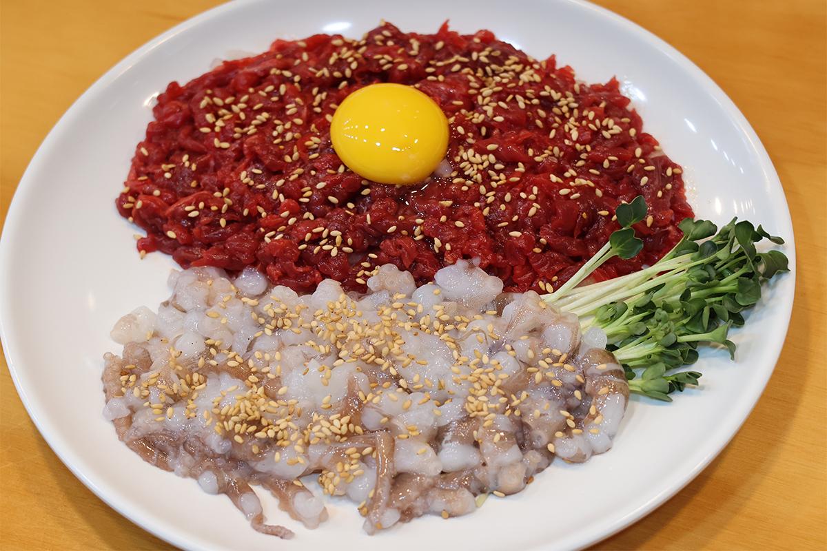 Yukhoe Tangtangi (Yukhoe y pulpo vivo picado) en Bakgane Yukhoe en el Mercado de Gwangjang, combinando sabores de carne cruda y pulpo, servidos con sésamo.