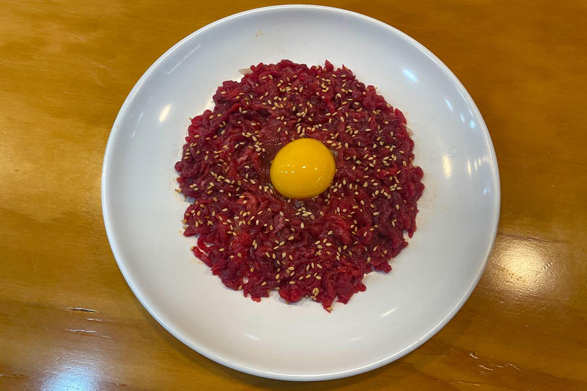 Plato de Yukhoe en Bakgane Yukhoe, un plato coreano tradicional de carne cruda aderezada con yema de huevo y semillas de sésamo.