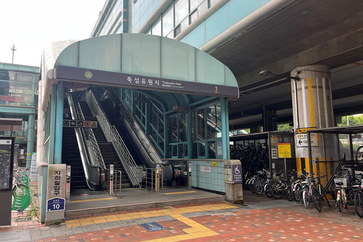 Entrance of Ttukseom Amusement Park Station showing steps and Korean signage in Seoul.