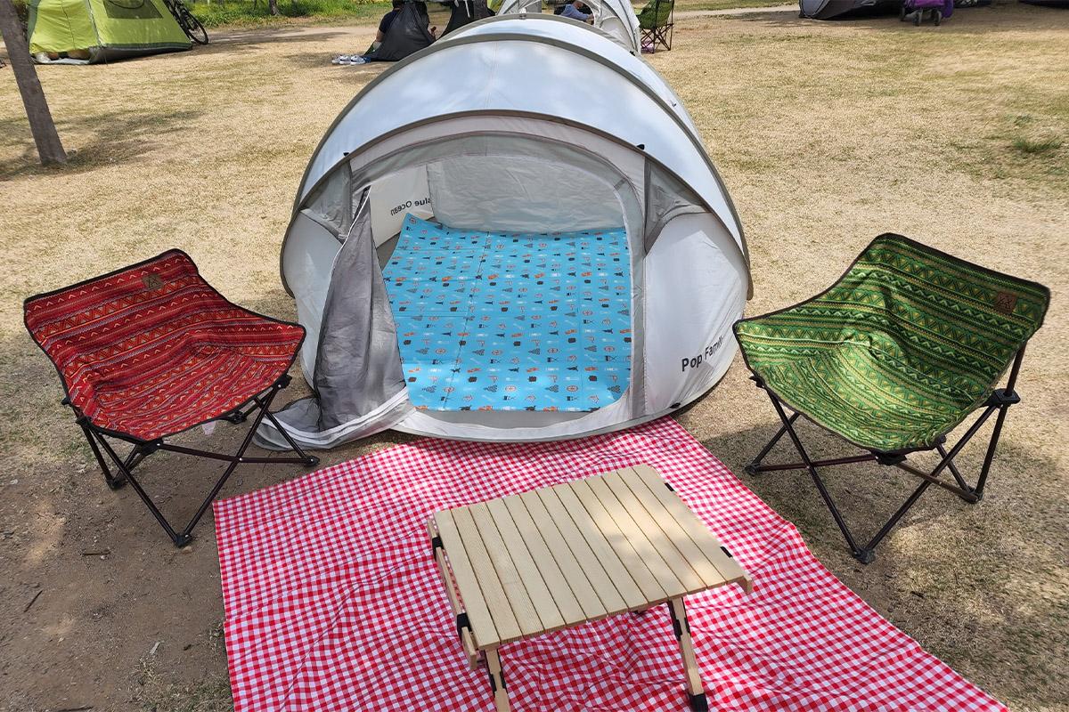 Close-up of a tent interior showing mats and pillows under the shade of trees by the river.