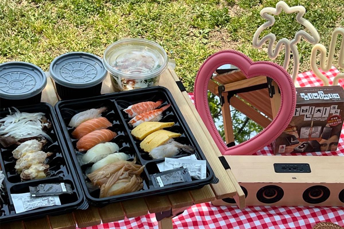 Portable picnic table surrounded by vibrant rugs and cushions for a relaxed Han River experience.