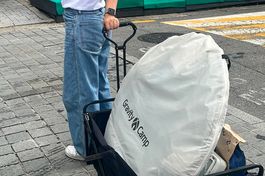 一名顧客正在商店外推著裝有露營工具的推車，準備前往漢江公園。