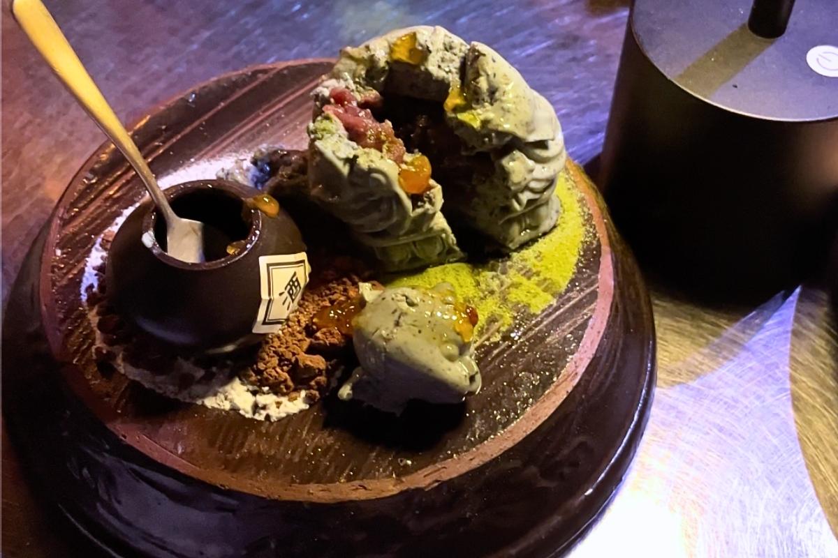 Внутренности десерта из черного кунжута в коктейль-баре Zoo Sindang, показывающие абрикосовый джем и крошки торта.